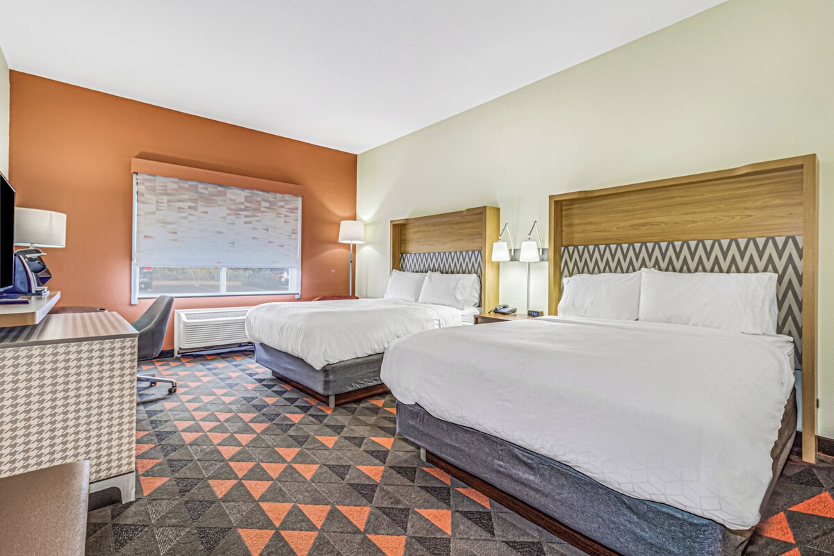 Ein Hotelzimmer mit zwei Betten, einem Schreibtisch und einem Stuhl.