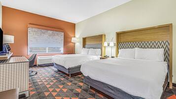 A hotel room with two beds, a desk, a chair, and a large window.