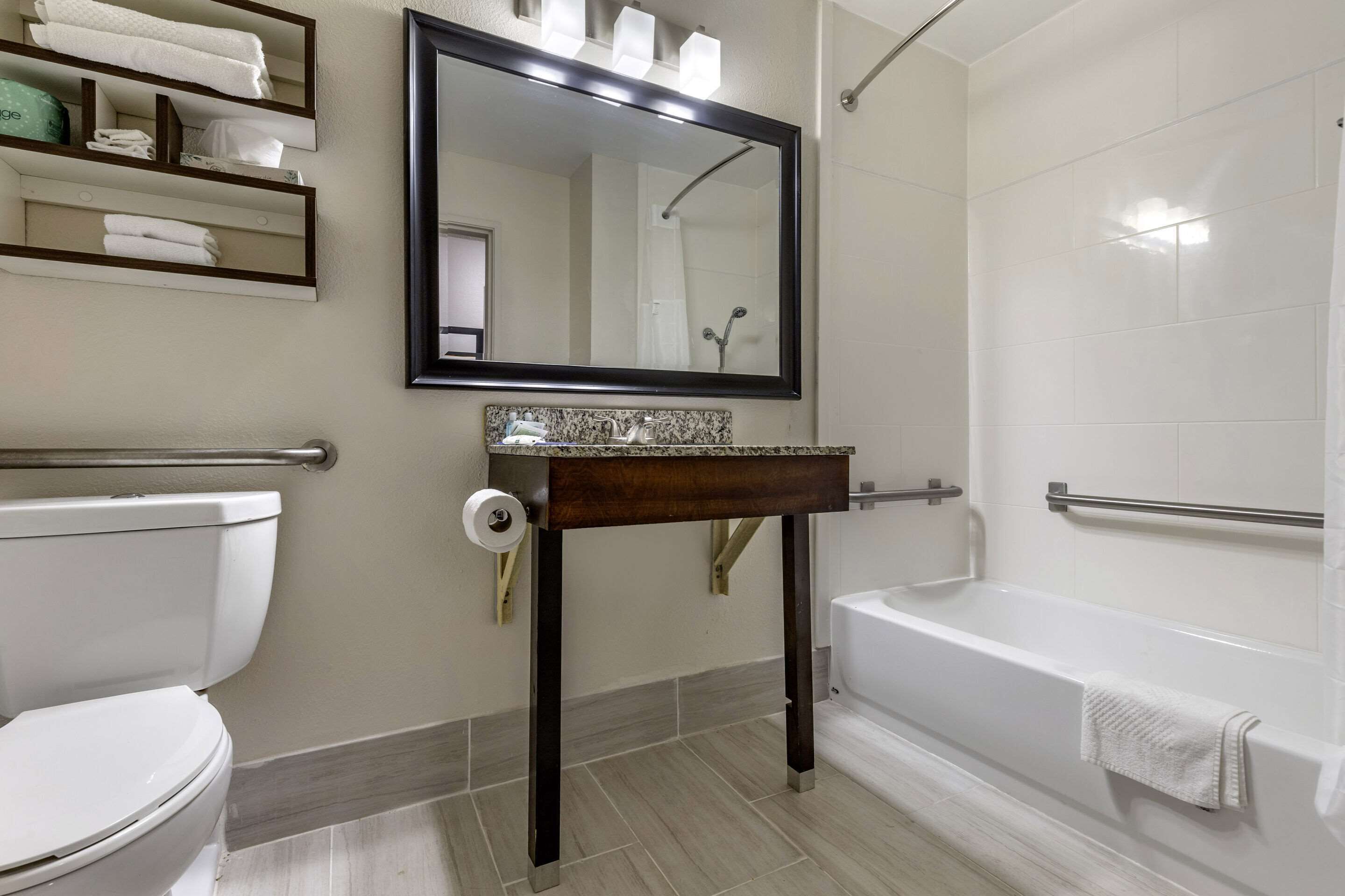 A bathroom with a toilet, sink, mirror, and bathtub.