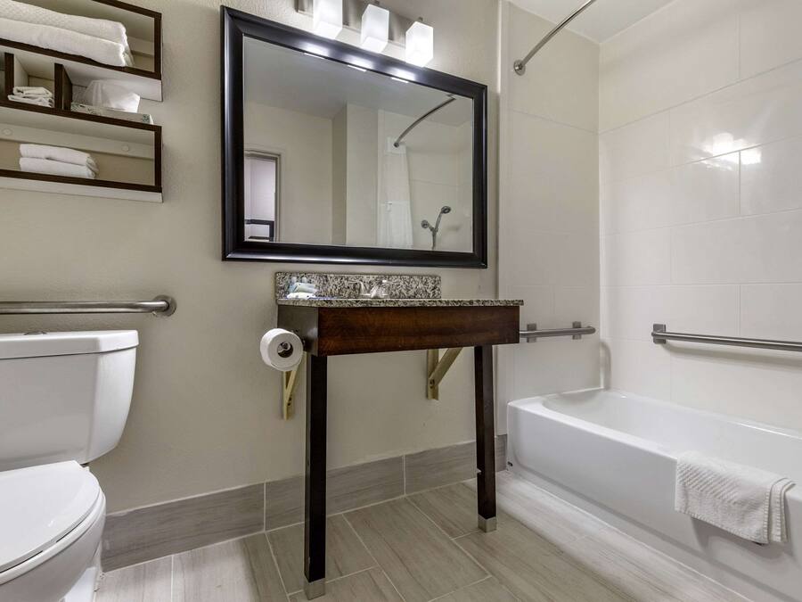 A bathroom with a toilet, sink, mirror, and bathtub.