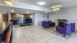 Um hall de entrada com balcão de recepção, assentos roxos, lareira e padrão de piso em padrão herringbone.