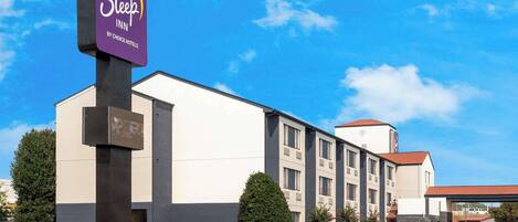 A Sleep Inn by Choice Hotels building with a parking lot and a blue car parked in front.