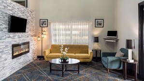 Un salon moderne avec un mur en pierre, un téléviseur à écran plat, un canapé, une table basse et une cheminée.