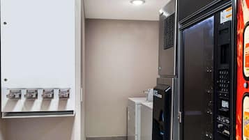 A laundry area with a wall-mounted dryer, a stacked washer, and a utility panel with four outlets.