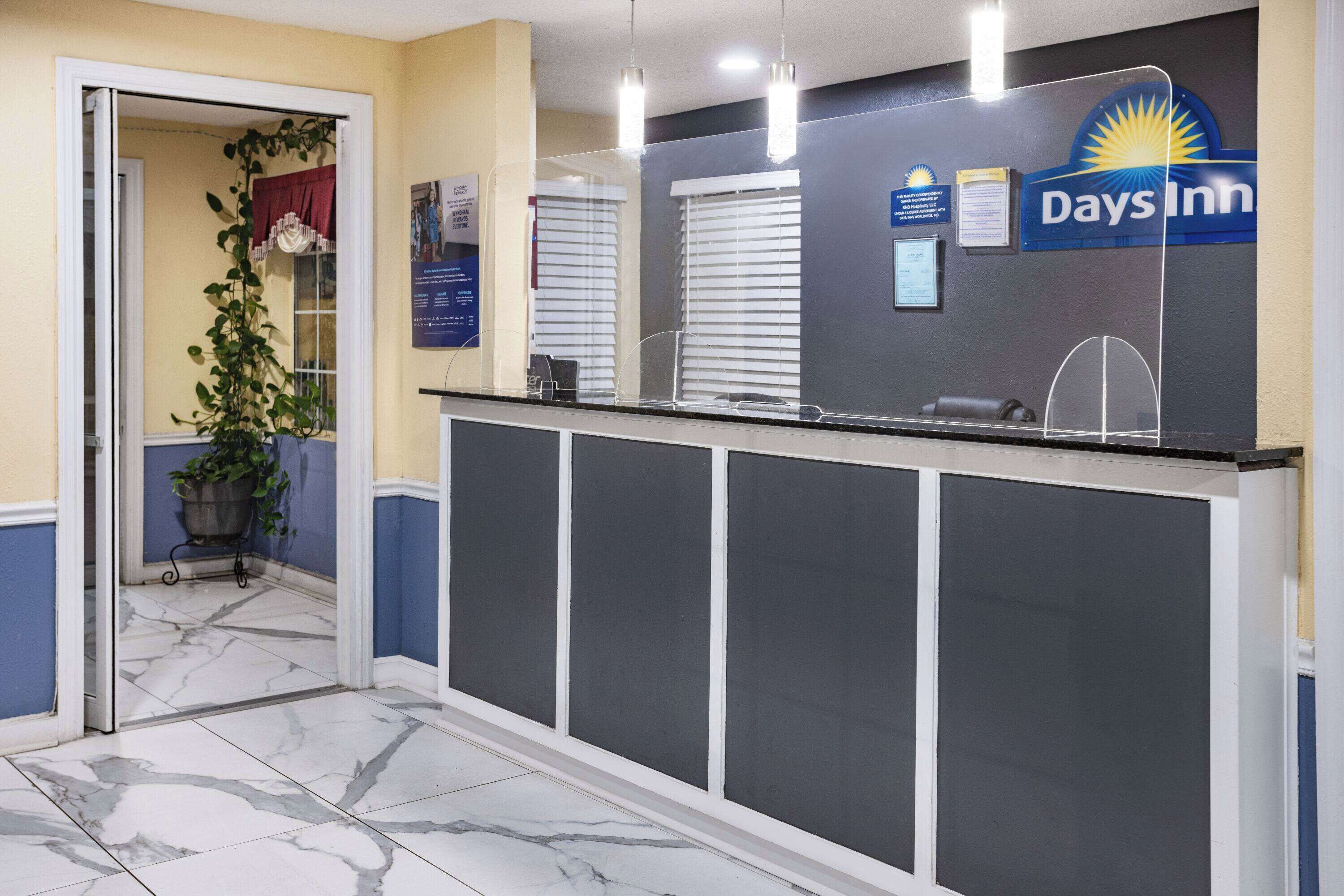 A reception area with a marble floor, a reception desk, a plant, and a sign for Days Inn.