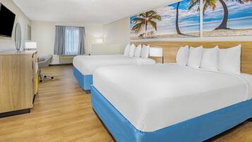 A hotel room with two beds, a desk, a chair, a TV, and a painting of a beach scene.