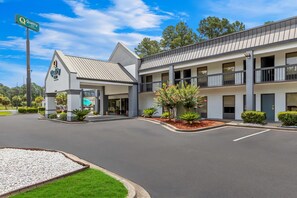 A hotel with a modern design, featuring a two-story structure, a covered entrance, and a landscaped front yard.