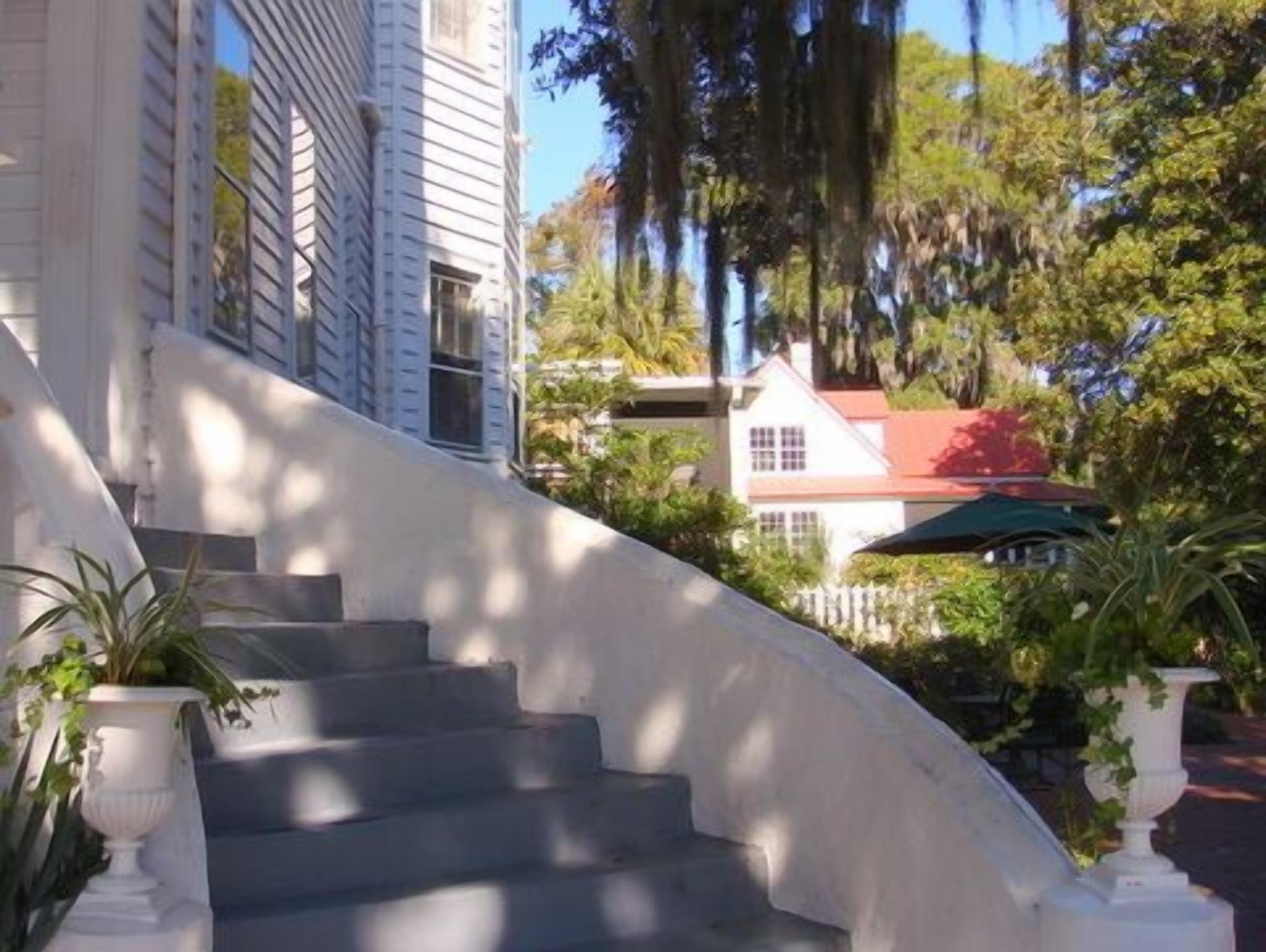 A curved staircase leading to a white building with a red roof.