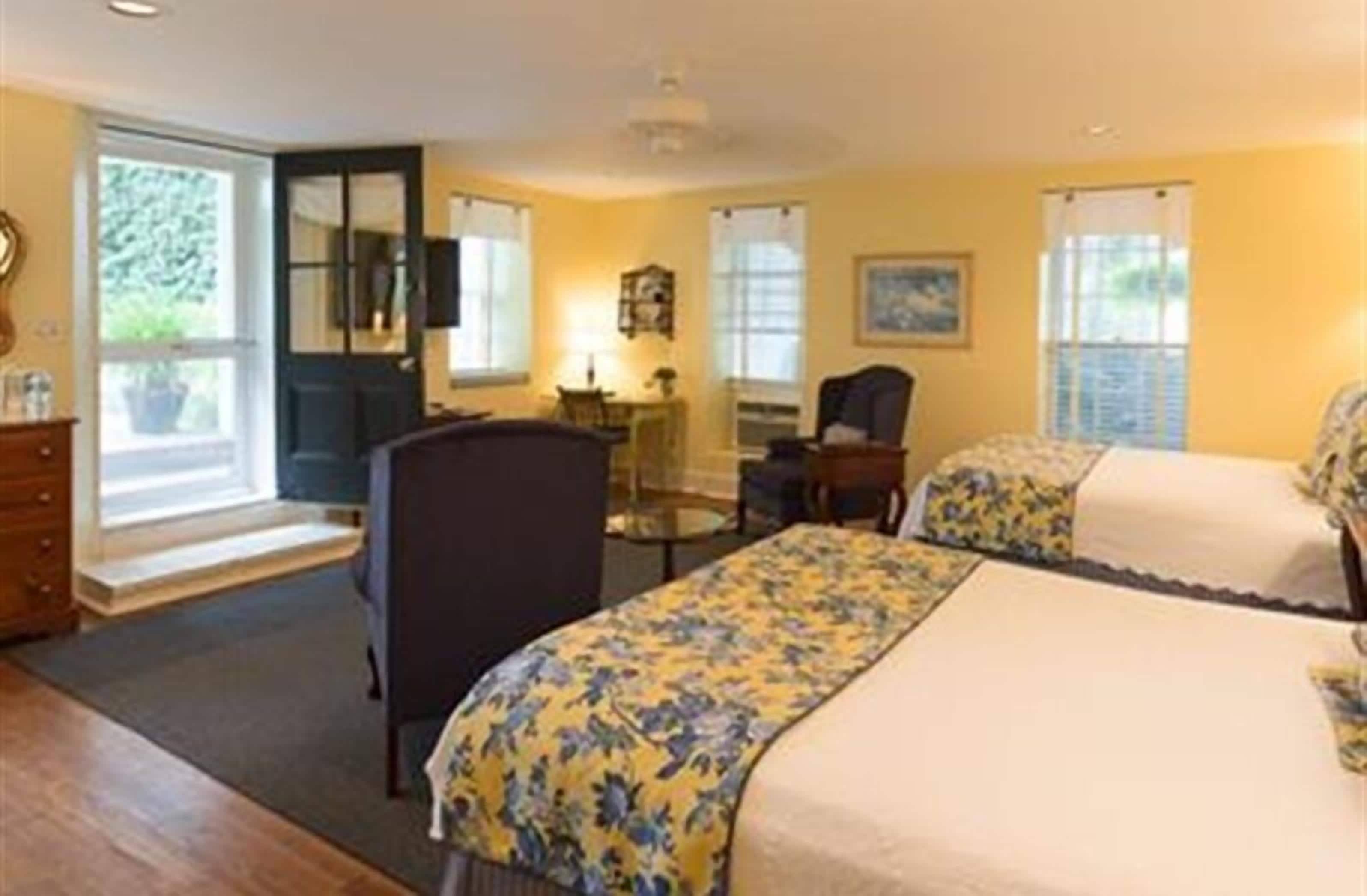A hotel room with two beds, a desk, a chair, and a window with curtains.