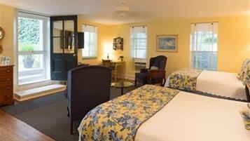 A hotel room with two beds, a desk, a chair, and a window with curtains.