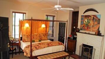 A bedroom with a four-poster bed, a fireplace, and a ceiling fan.