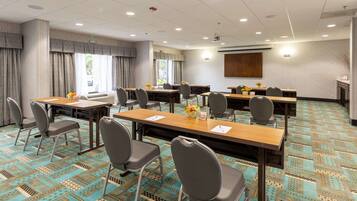 A conference room with multiple tables and chairs, a projector screen, and a patterned carpet.