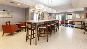 Une cuisine moderne dotée d’un îlot central, de tabourets de bar et de luminaires suspendus.