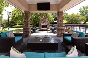 An outdoor patio area with wicker furniture, a stone fireplace, and a flat-screen TV mounted above. - Hampton Inn Columbia I-26/Harbison Blvd. (Columbia)