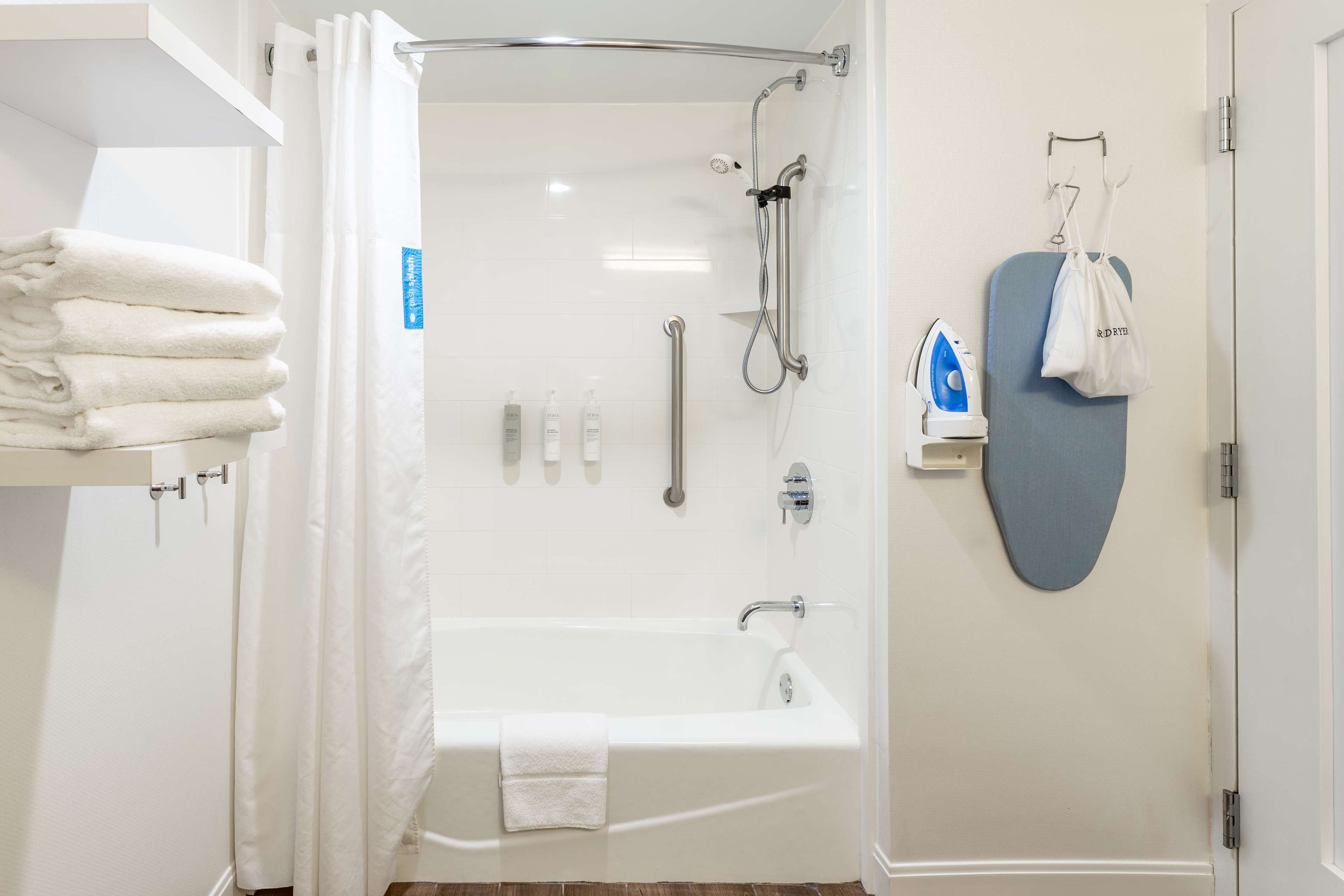 Ein modernes Badezimmer mit bodengleicher Dusche, Badewanne, Toilette und Handtuchhalter.