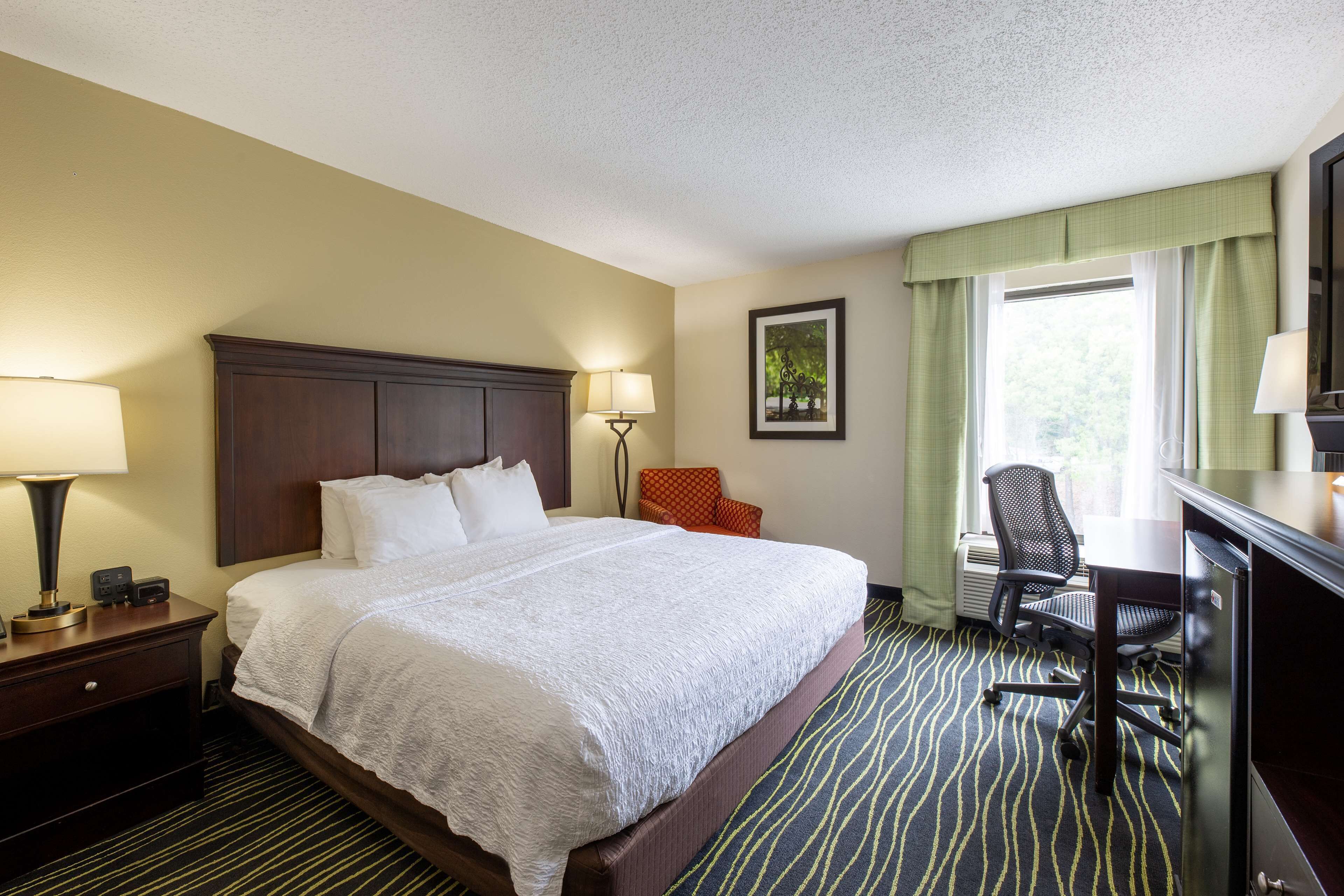 Une chambre d’hôtel avec un grand lit, un bureau et une chaise.
