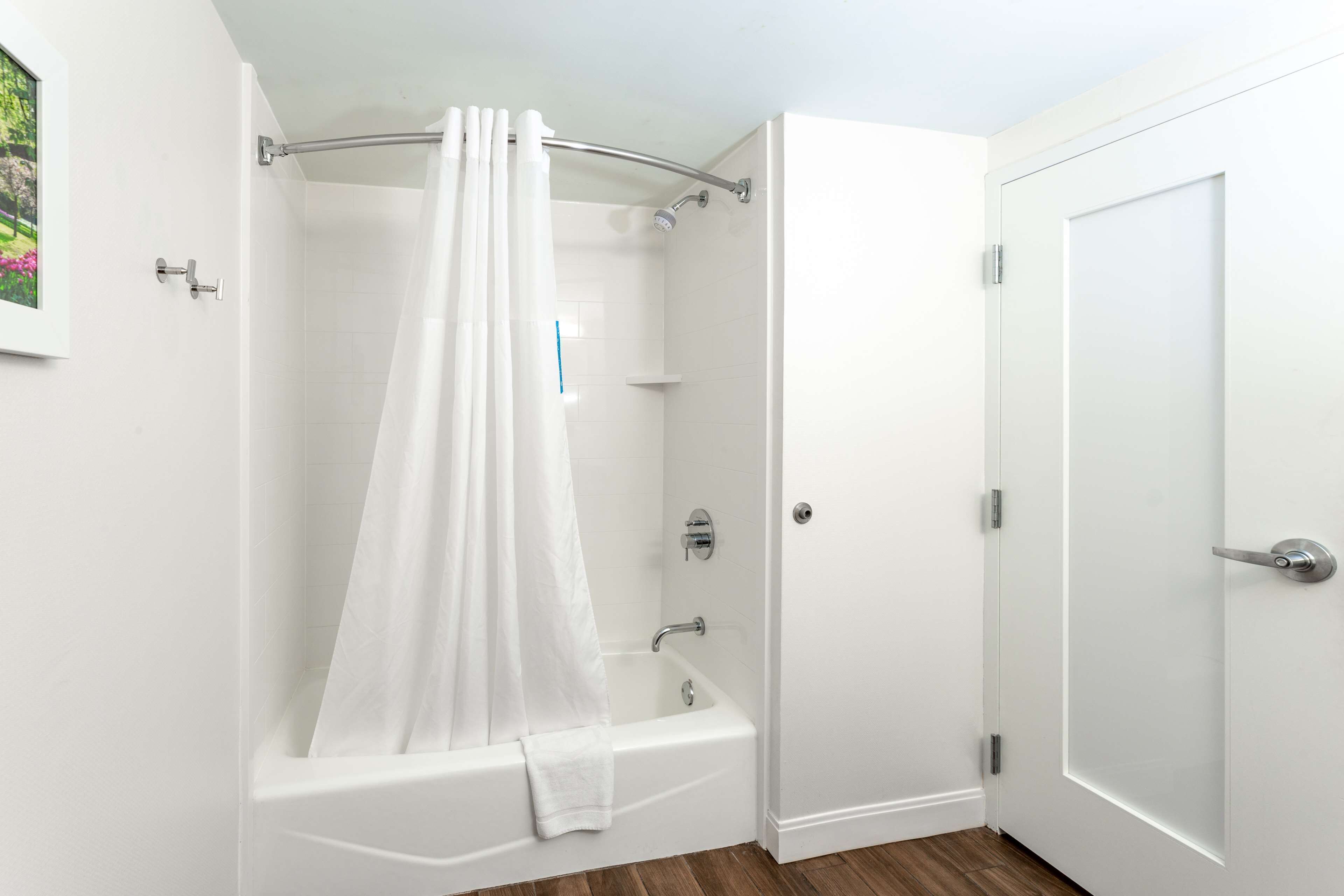 Un baño con una bañera blanca, cortina de ducha y una puerta.