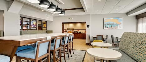 A hotel lobby with a bar area, seating, and a painting on the wall.
