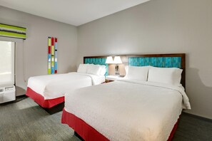 Habitación de hotel con dos camas, una ventana, un equipo de aire acondicionado y una lámpara fijada a la pared.