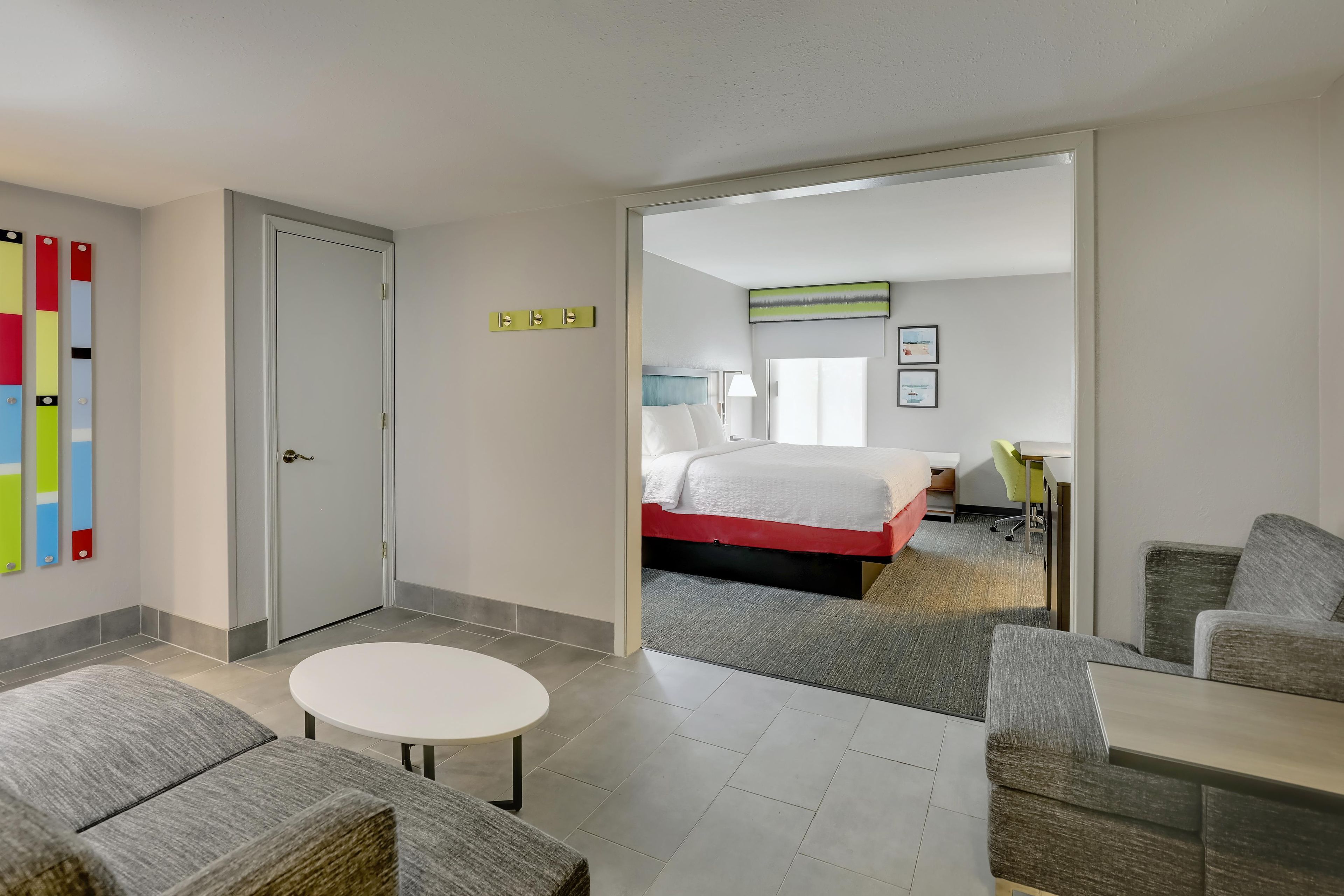 Una habitación de hotel con una cama, un escritorio, una silla y una pequeña mesa redonda.