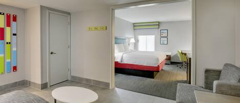 A hotel room with a bed, a desk, a chair, and a small round table.