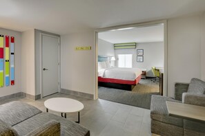 Una habitación de hotel con una cama, un escritorio, una silla y una pequeña mesa redonda.