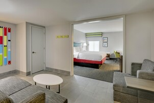 Una habitación de hotel con una cama, un escritorio, una silla y una pequeña mesa redonda.