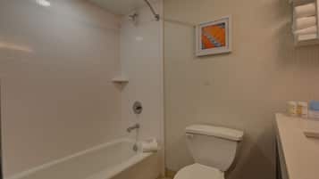 Een badkamer met een badkuip, toilet en een ingelijste foto aan de muur.