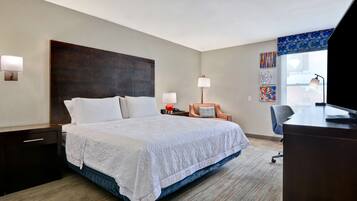 A hotel room with a large bed, a desk, a chair, and a window with a view.