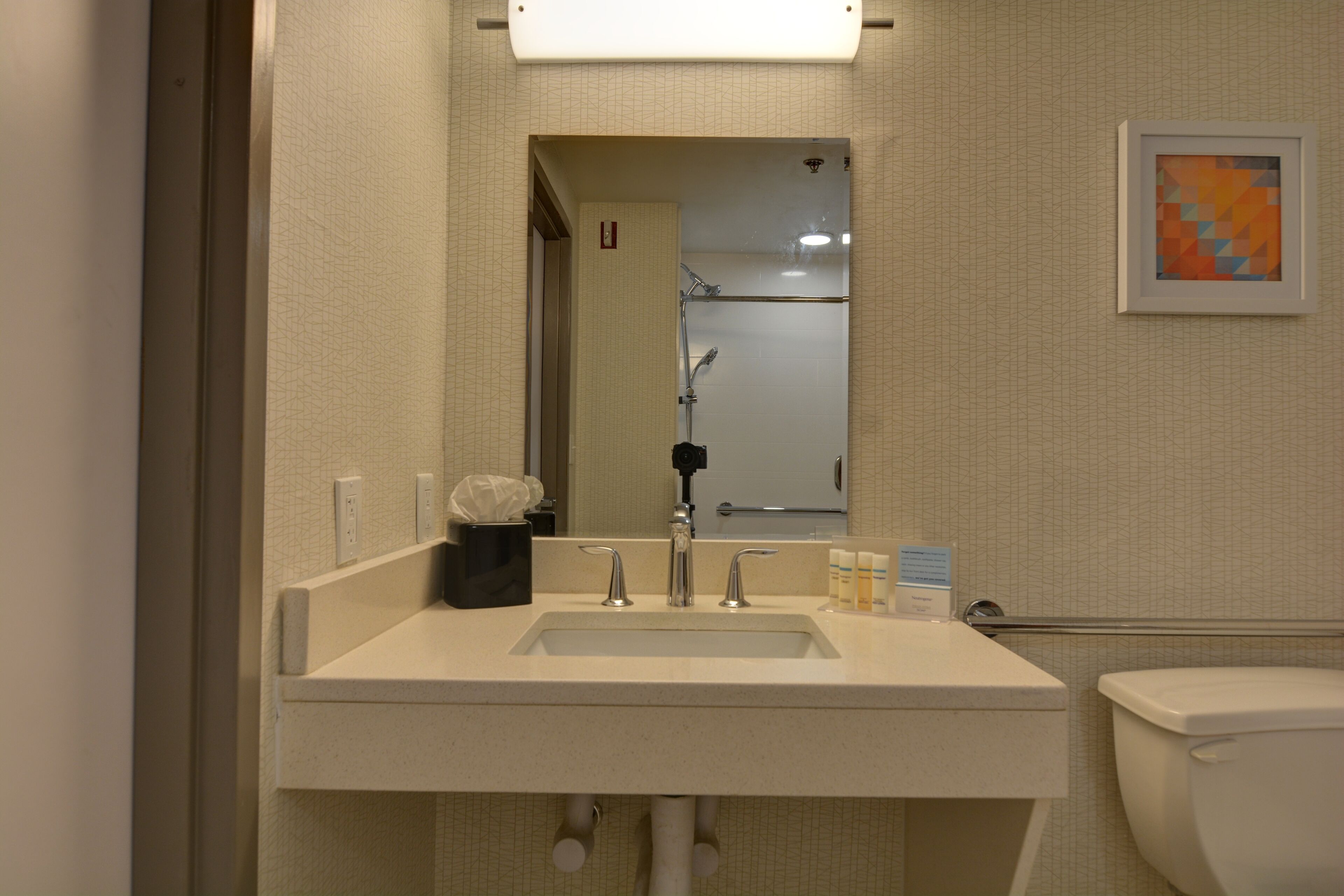 Un baño con lavabo, espejo e inodoro.