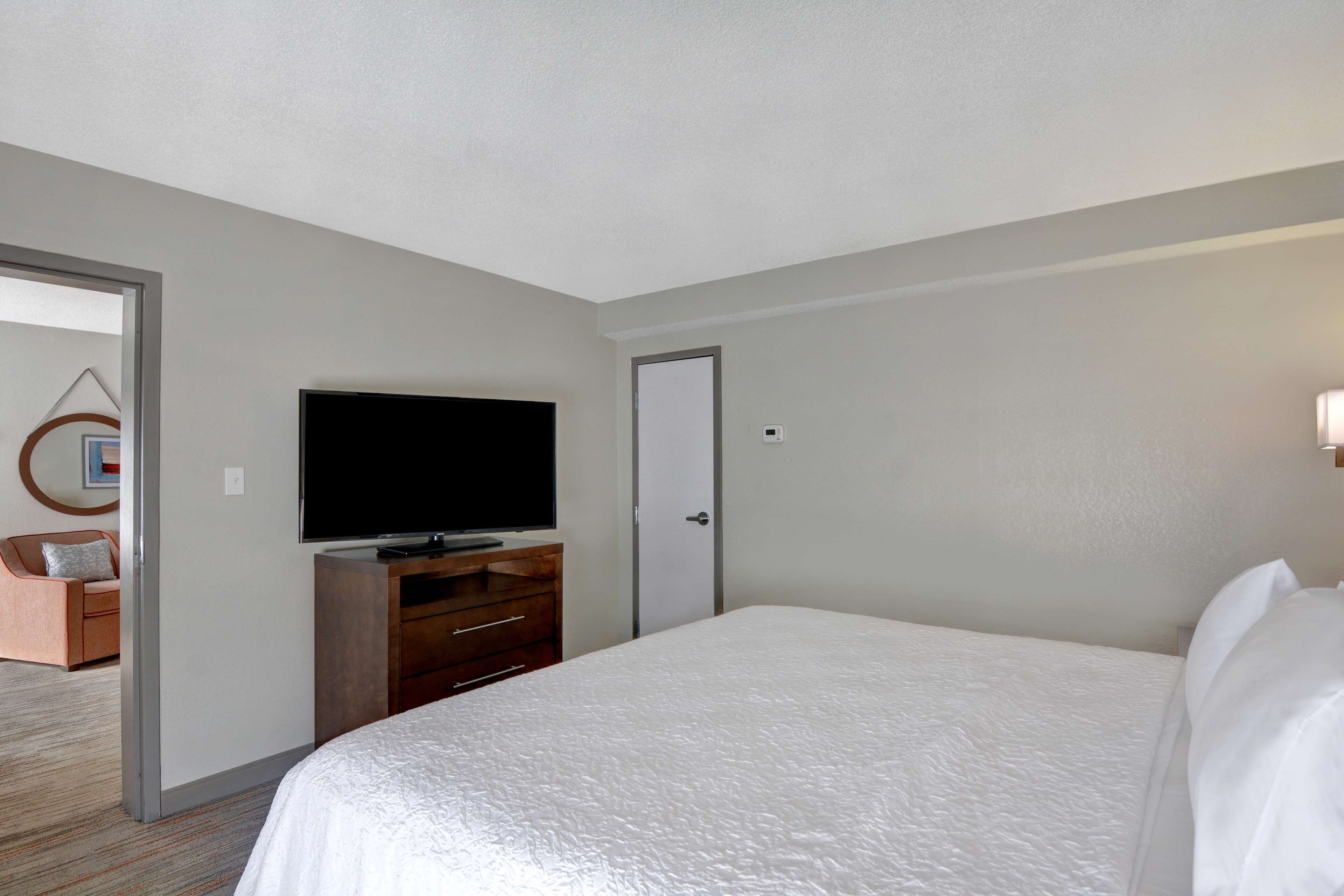 A hotel room with a large bed, a television on a wooden dresser, and a door.