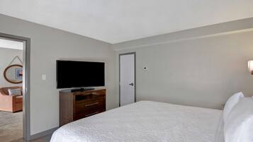 A hotel room with a large bed, a television on a wooden dresser, and a door.