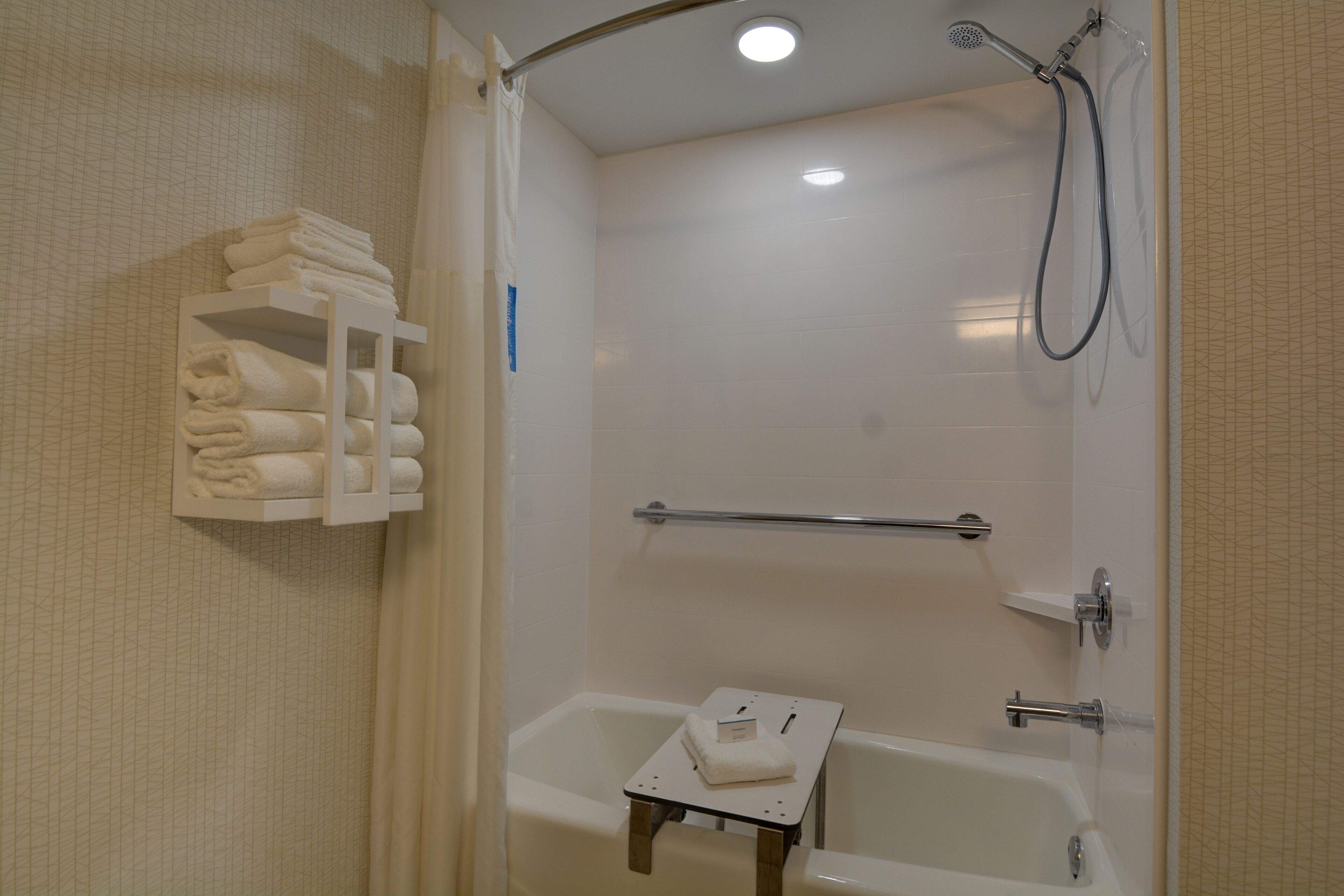 Une salle de bain équipée d’une baignoire, d’une douche et d’un porte-serviettes avec des serviettes pliées.