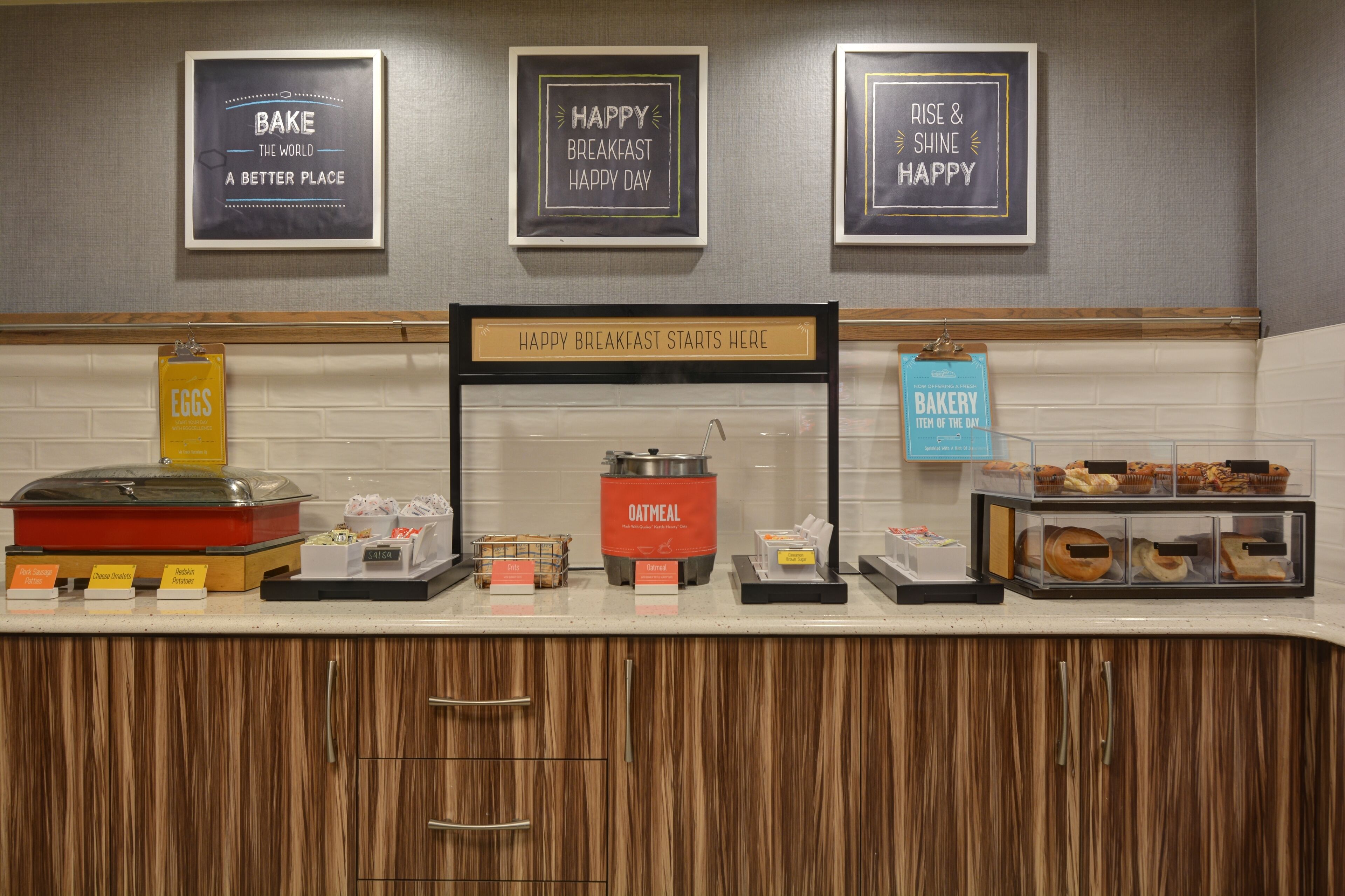 Un espace buffet pour le petit-déjeuner avec des présentoirs de nourriture clairement identifiés, proposant des œufs, des céréales, du porridge et des produits de boulangerie.