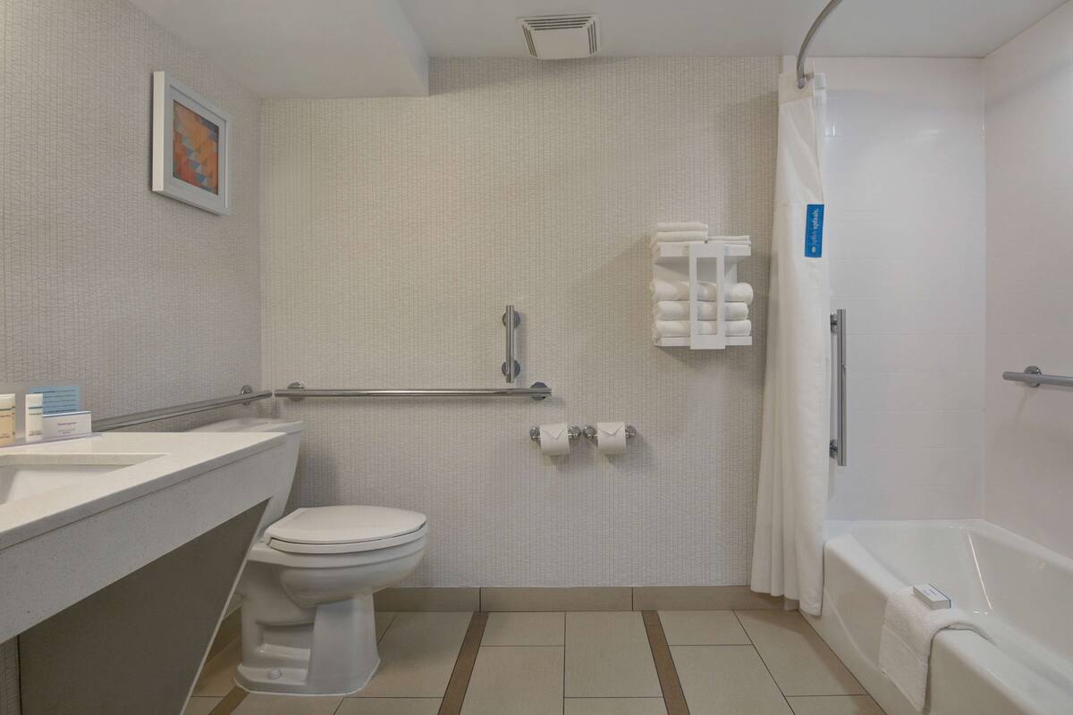 A bathroom with a toilet, sink, shower, and a towel rack.