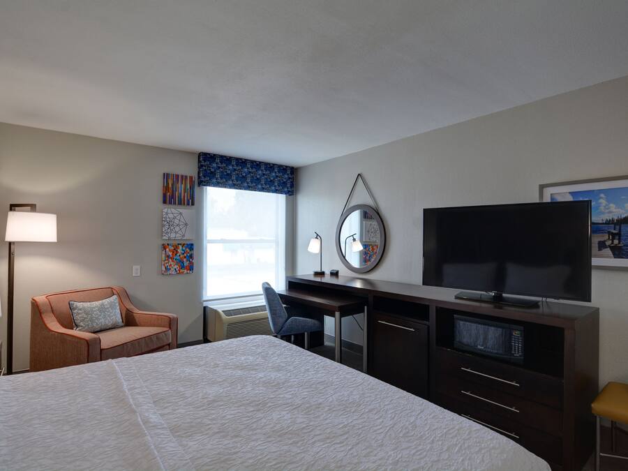 Ein Hotelzimmer mit Bett, Schreibtisch, Fernseher und einem Sessel.