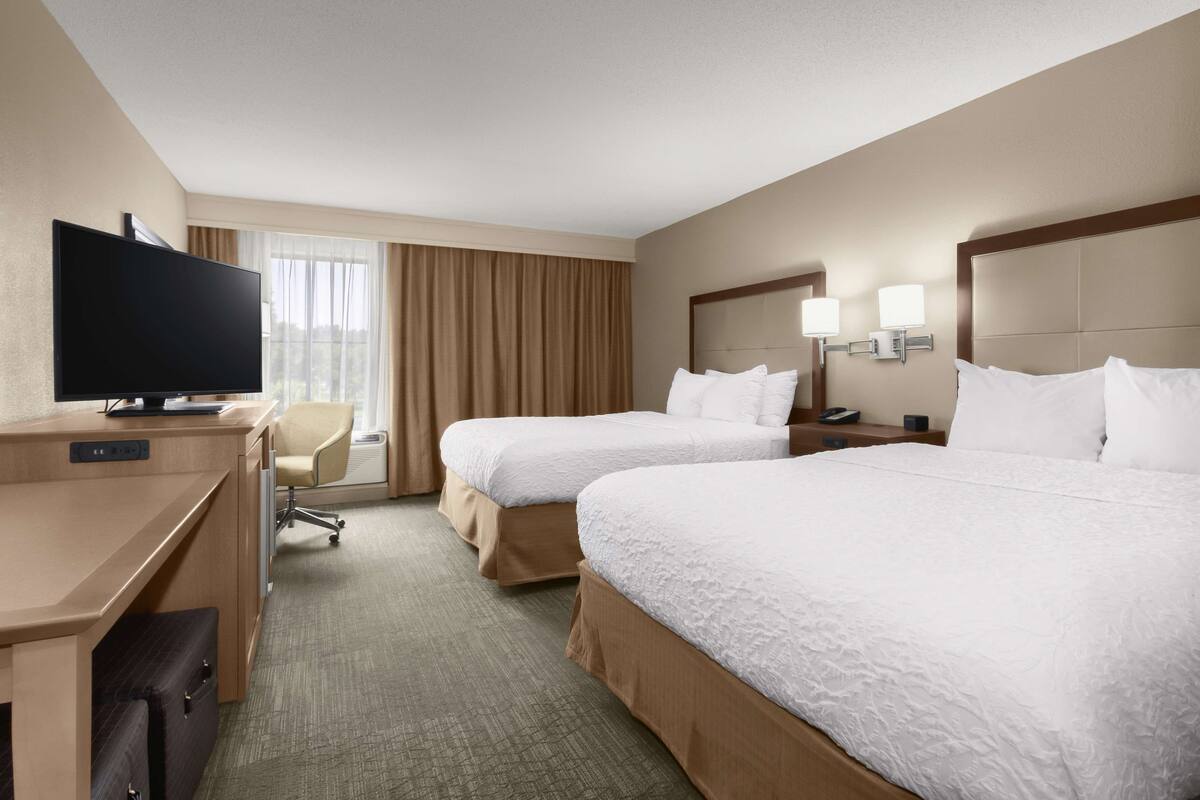 Une chambre d’hôtel avec deux lits, un bureau, une télévision et une chaise.