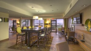 Un vestíbulo de hotel con zona de comedor, bar y vista al puerto deportivo.