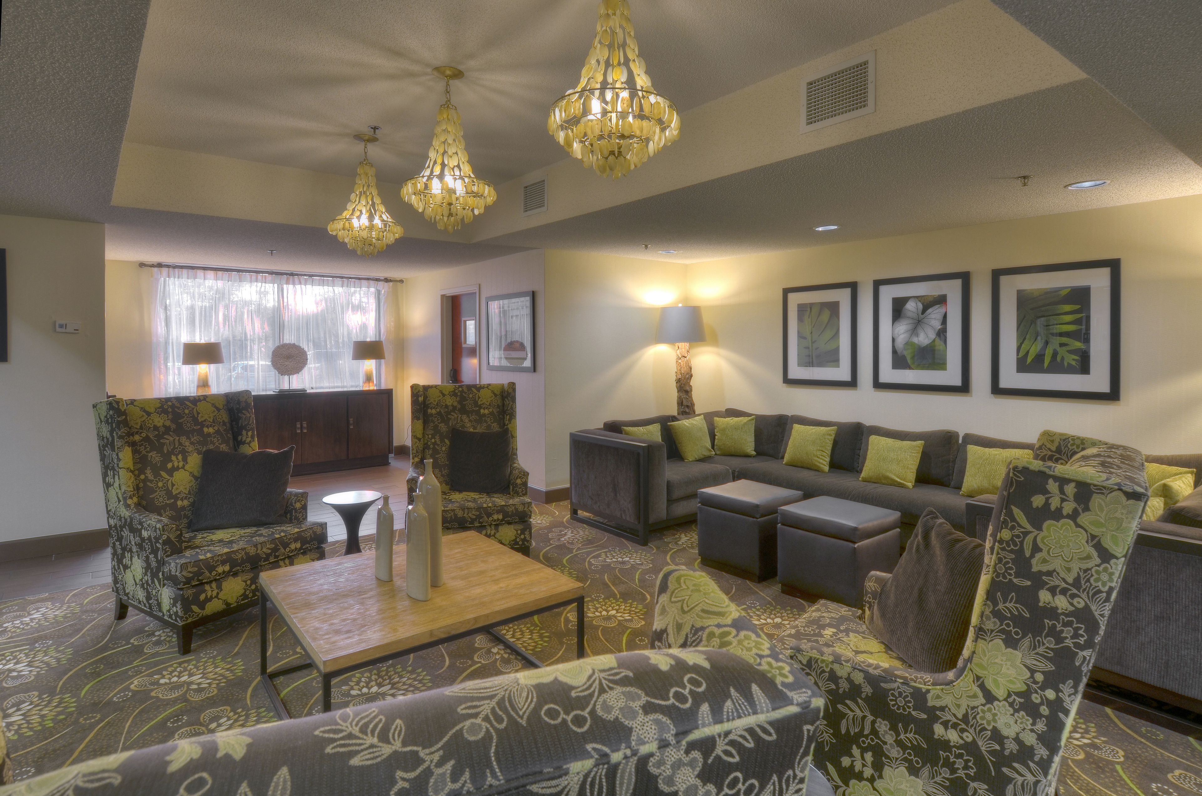 A spacious living room with a sofa set, armchairs, a coffee table, and decorative lamps.