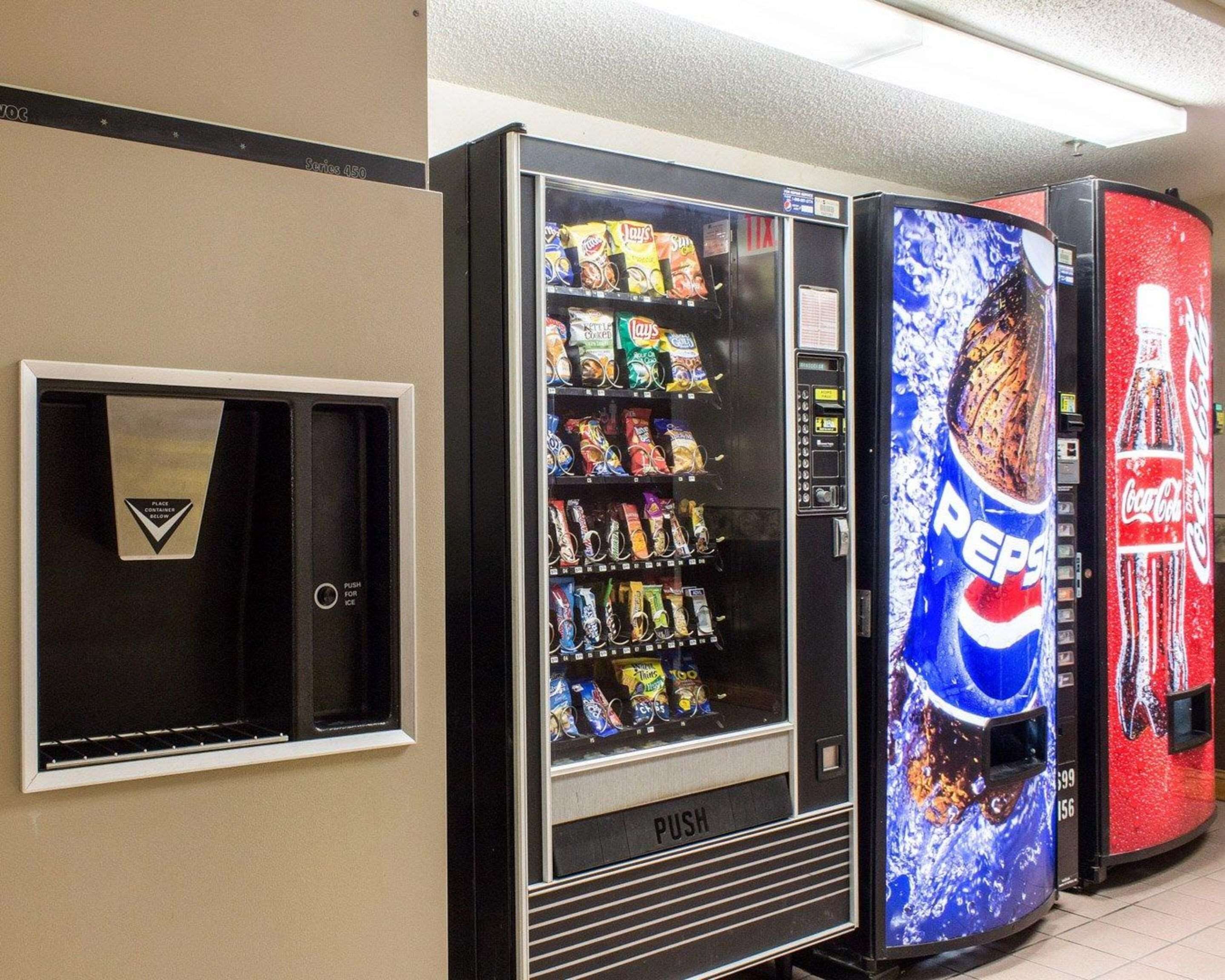 En automatapparat med en reklam för Pepsi, en annan för Coca-Cola och ett litet kylskåp med en skylt som visar var man kan hitta kalla drycker.