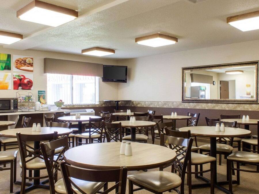 Un restaurante con mesas y sillas redondas, un televisor en la pared y un espejo grande.