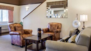 A living room with leather armchairs, a sofa, a coffee table, a mirror, and a lamp. - Quality Inn Brandon - Sioux Falls (Brandon)