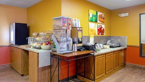 A breakfast bar with a coffee machine, cereal dispensers, and a fruit bowl. - Quality Inn Huron (Huron)