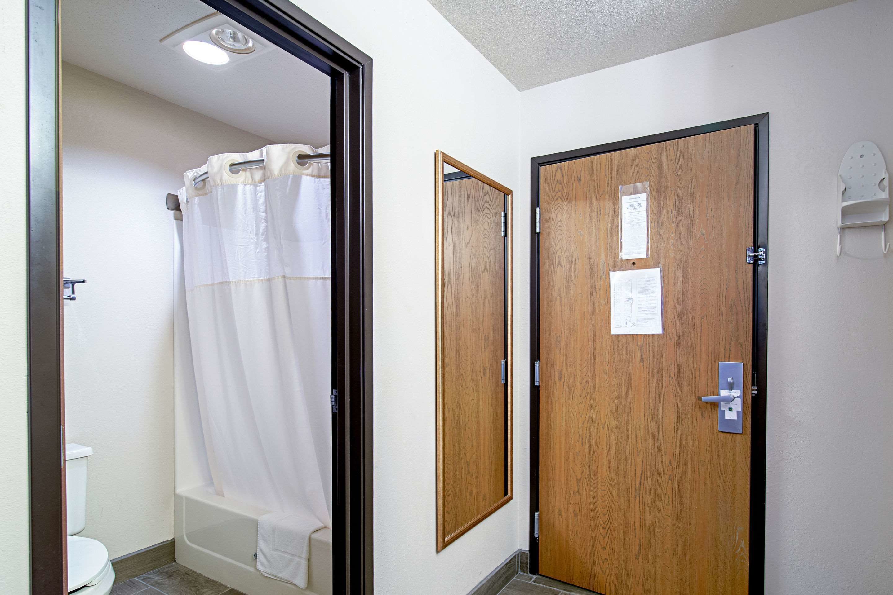 A bathroom with a shower curtain, a wooden door, and a white towel rack.
