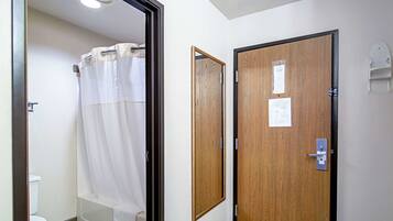 A bathroom with a shower curtain, a wooden door, and a white towel rack.