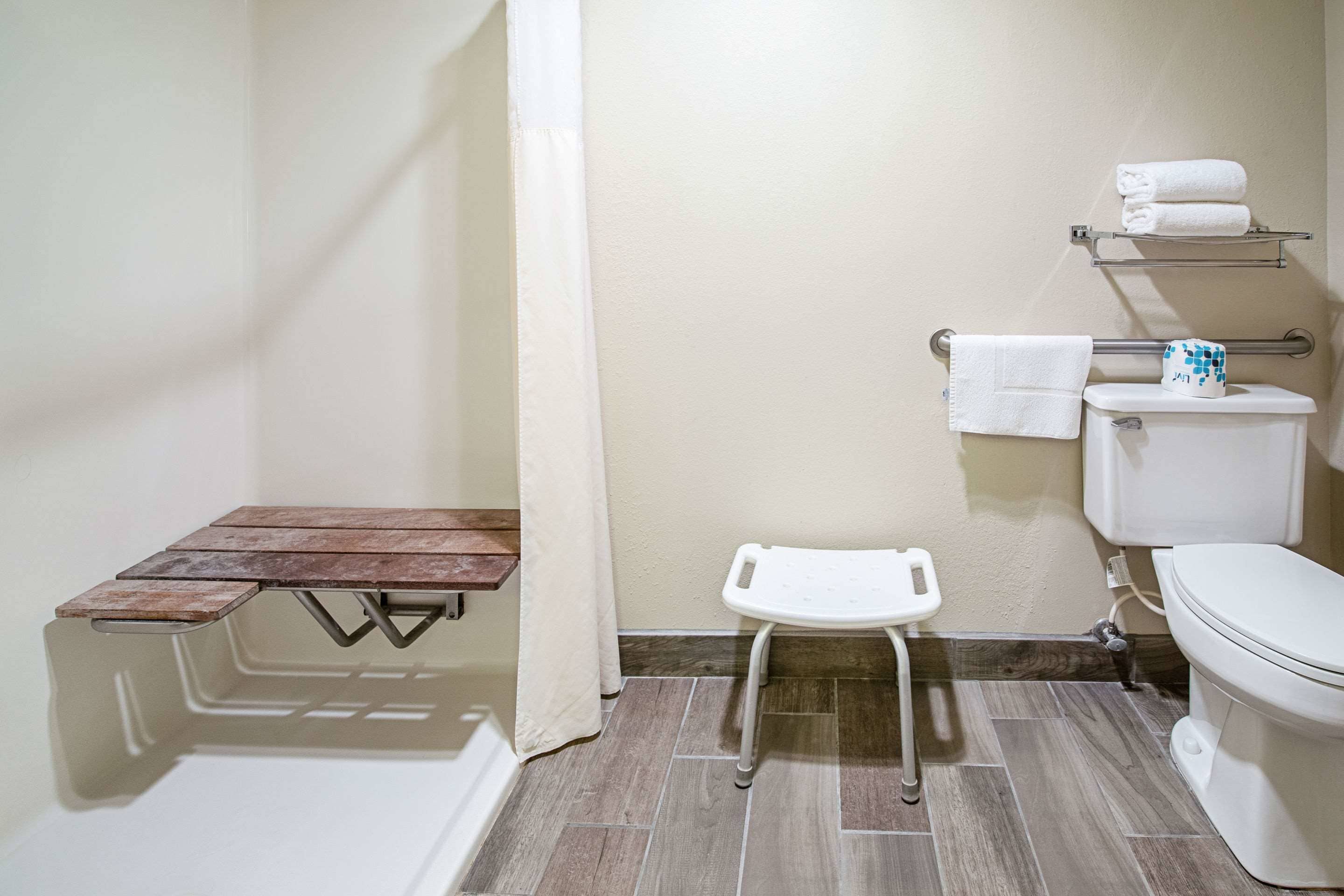 A bathroom with a shower, toilet, and a small table with a towel.