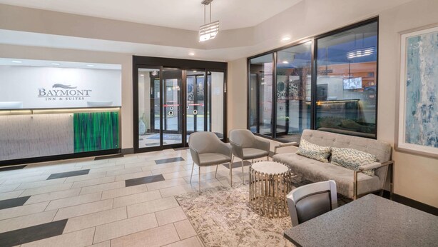A modern hotel lobby with a reception desk, seating area, and large windows. - Baymont by Wyndham Franklin/Cool Springs (Franklin)