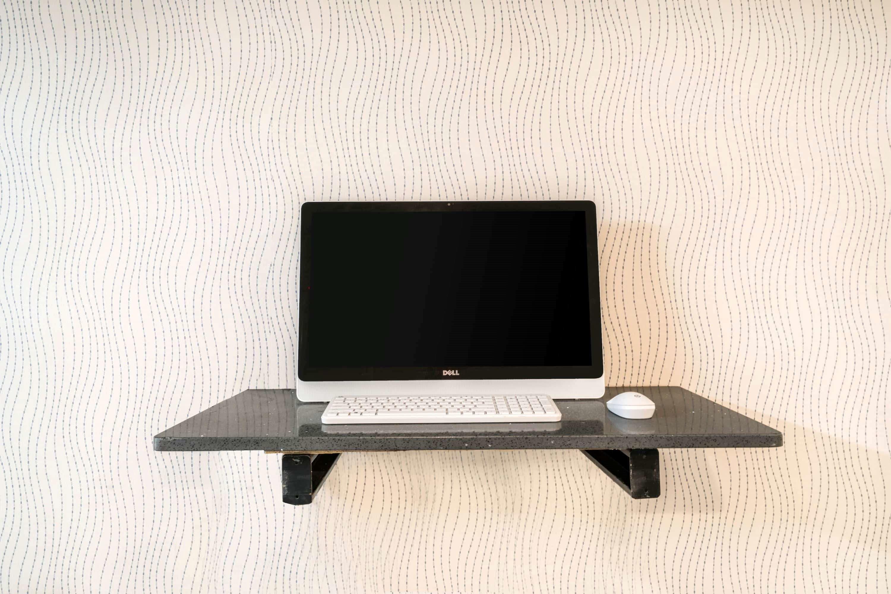 En Dell laptop på et sort stativ med et tastatur og en mus.
