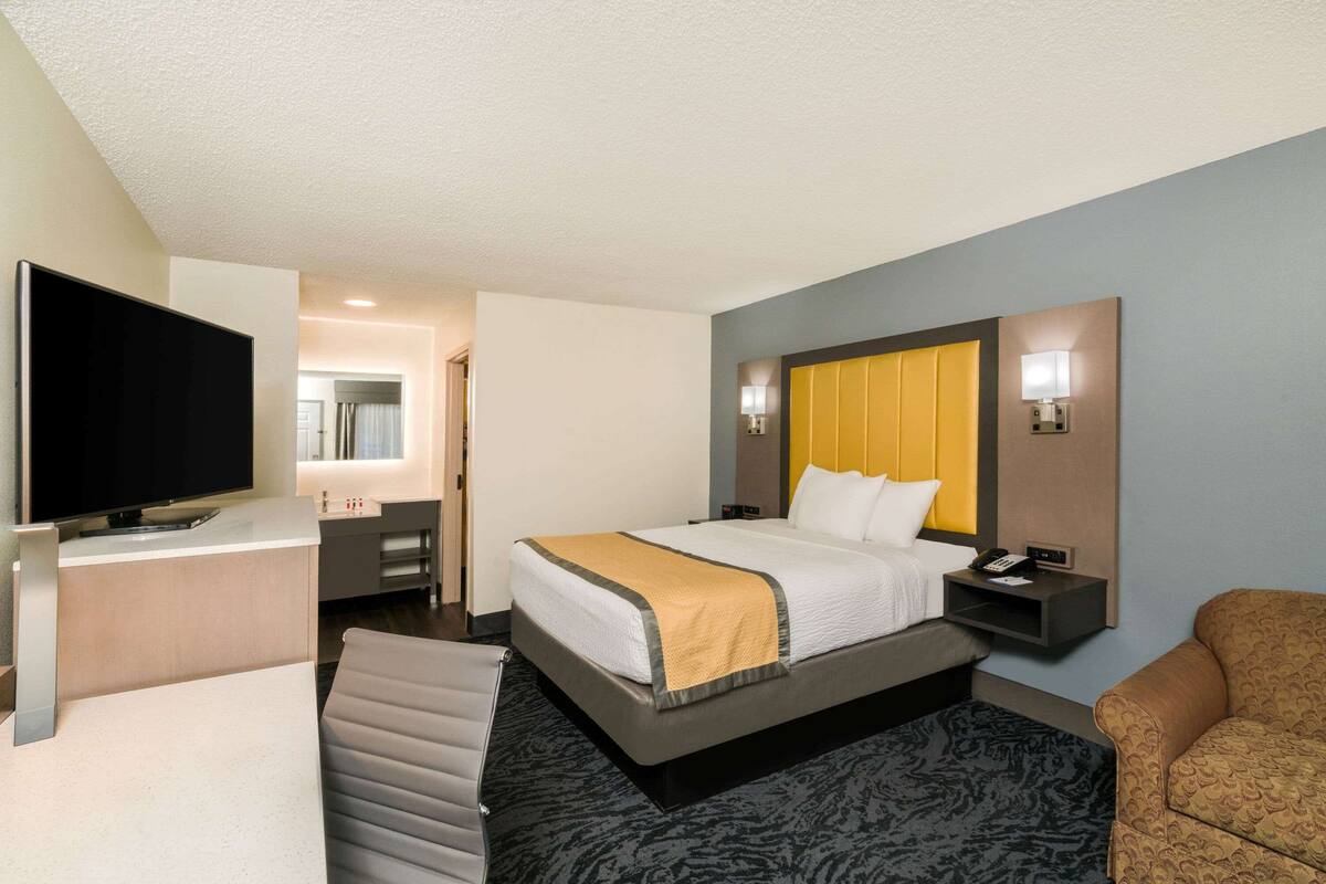 Una habitación de hotel con una cama, televisión, escritorio y una silla.