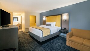 A hotel room with a large bed, a television, a desk with a lamp, and a sofa. - Baymont by Wyndham Franklin/Cool Springs (Franklin)